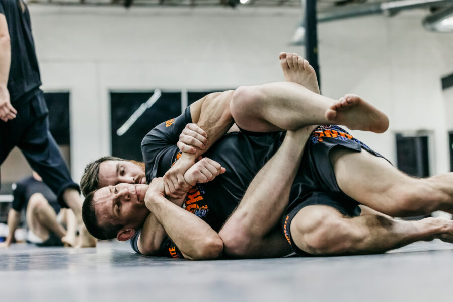 Black Belt Professor Matt Vernon trains situational rolling from the back mount with a student working to escape the the body lock while the white belt student tries to keep position