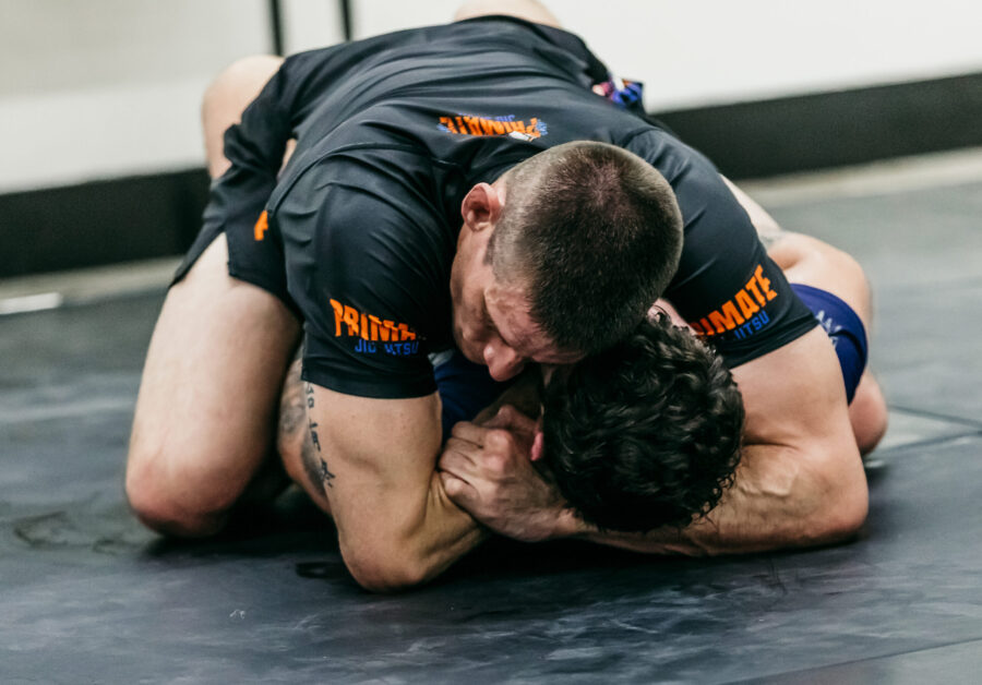 Black belt professor Matt Vernon applies a nogi Ezekiel choke strangle hold finish from the mount position during live situational nogi submission grappling training during an adult nogi BJJ class at Primate Jiu Jitsu in Tulsa OK