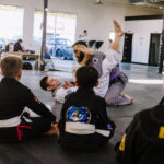 Black belt professor Matt Vernon demonstrates an arm bar submission attack from the closed guard on purple belt assistant coach Chris Stafford during a kids BJJ class at Primate Jiu Jitsu in Tulsa OK