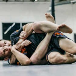 Black Belt Professor Matt Vernon trains situational rolling from the back mount with a student working to escape the the body lock while the white belt student tries to keep position