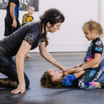 Black belt instructor Kendall Vernon of Primate Jiu Jitsu in Tulsa OK coaches two young girls during kids nogi BJJ class from the mount position while all wear Gaidama grappling gear