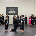 Black belt professor Matt Vernon rewards hardworking youth students and brothers Sam and Liam with gray belts during a kids BJJ promotion ceremony at Primate Jiu Jitsu in Tulsa OK